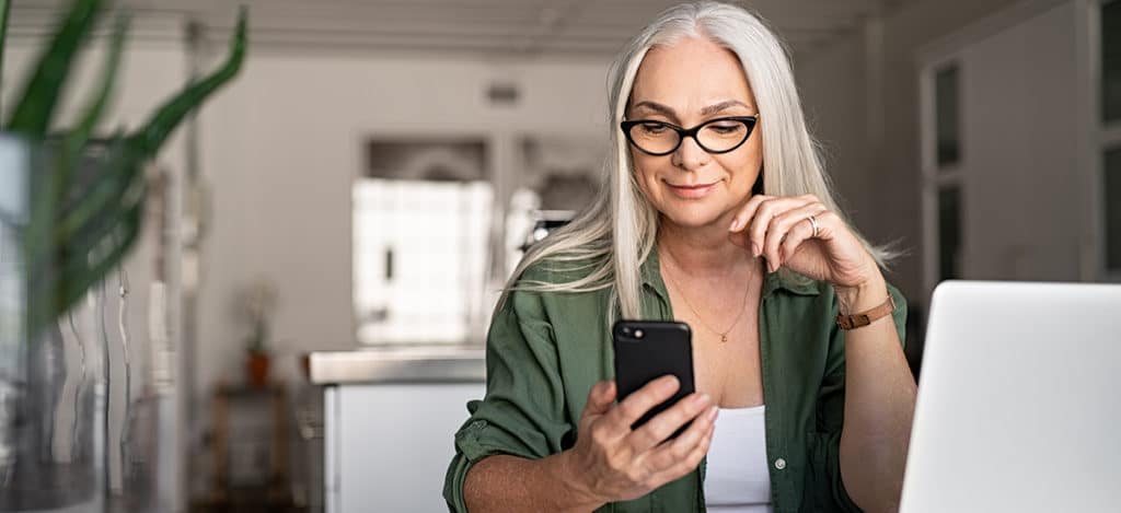 a mature woman with Bluetooth heating aids connecting her phone with hearing technology